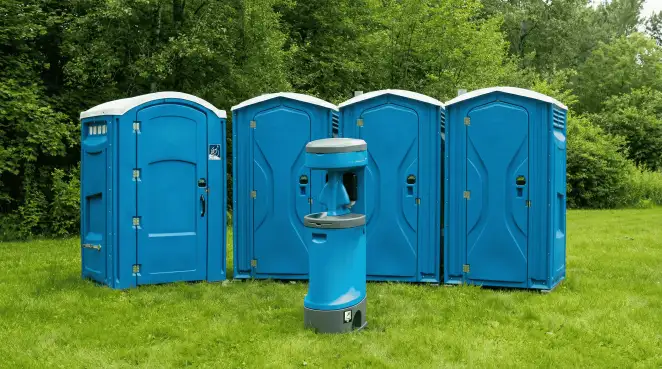 Four blue portable toilets and a matching hand washing station on grass near trees, a common sight at local outdoor events in Las Vegas, NV